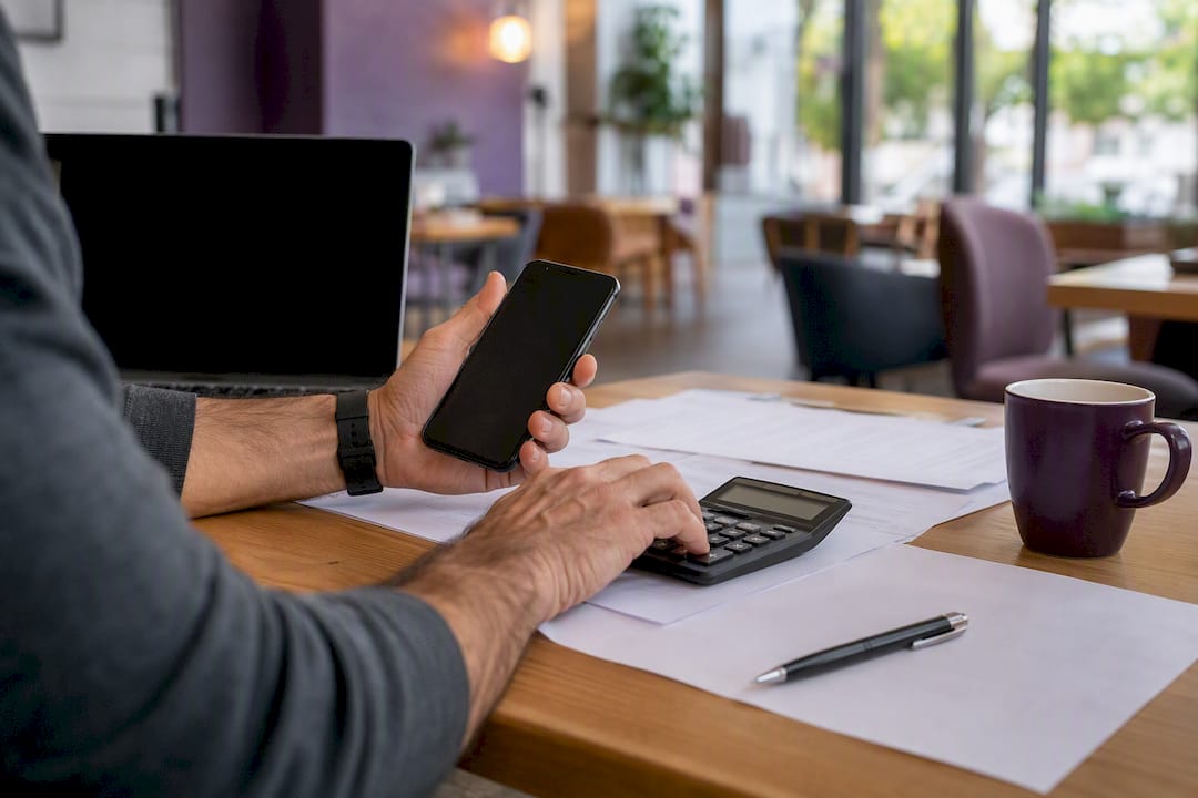 Hands working on calculator and phone for rate package